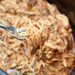 a fork holding up cooked shredded chicken