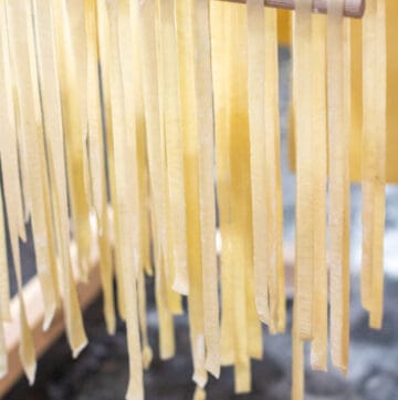 linguine pasta drying on a hanging rack.