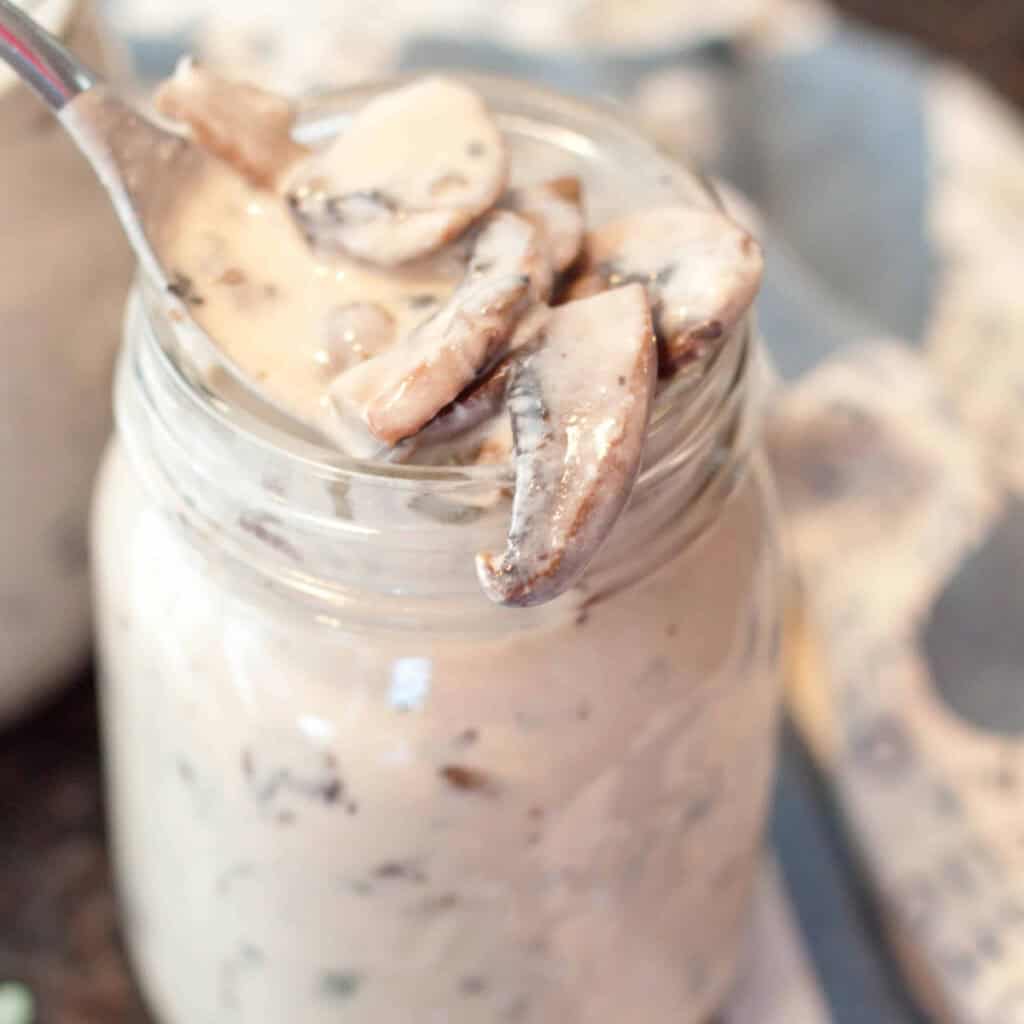 a mason jar of cream of mushroom soup with a spoon of mushrooms.