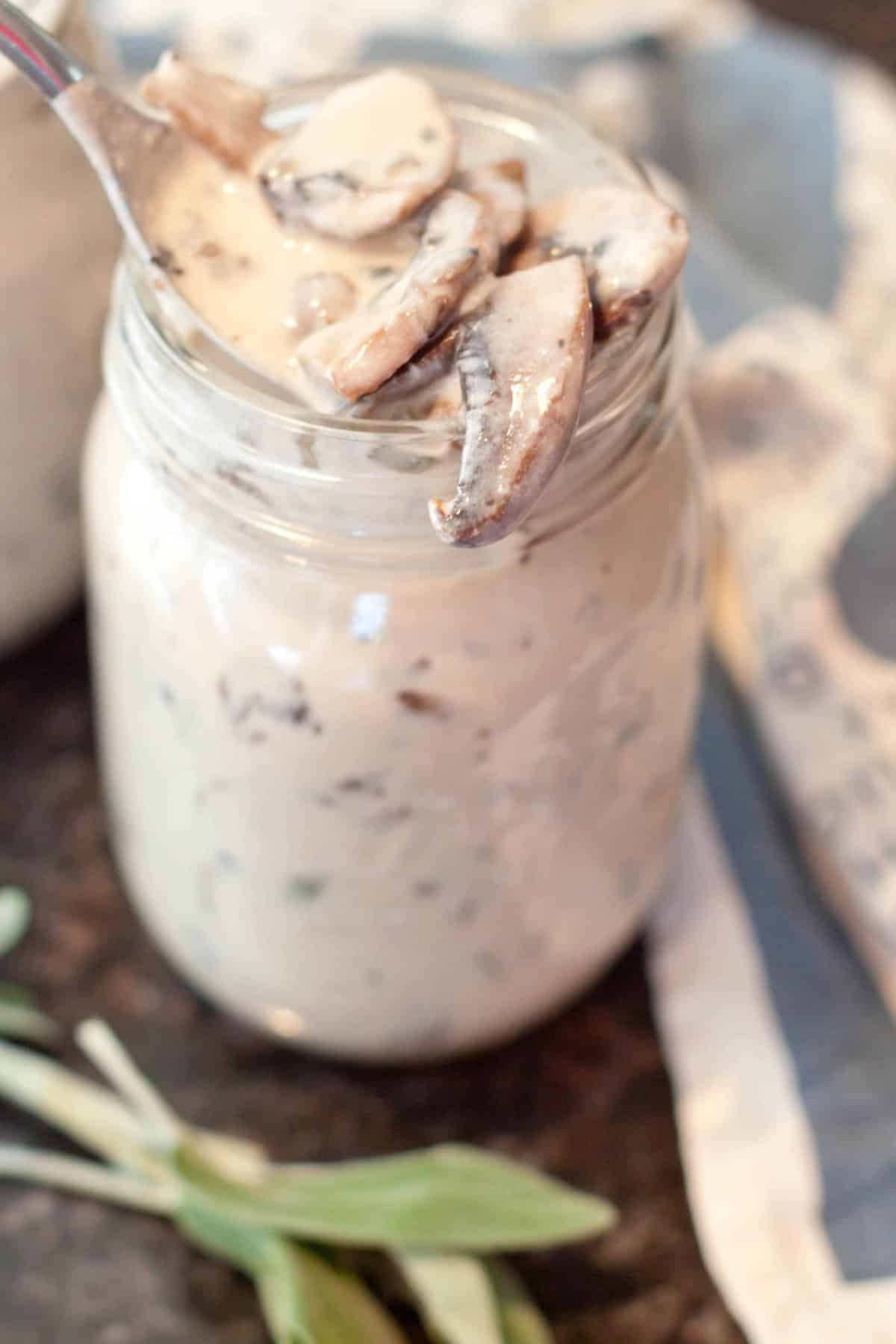 a mason jar of cream of mushroom soup with a spoon of mushrooms.