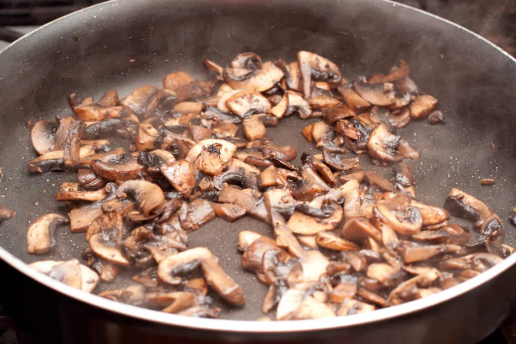 mushrooms being sautéed in a pan. 