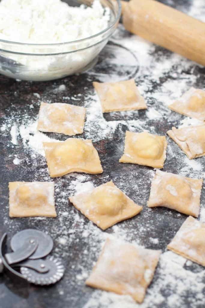 homemade fresh ravioli on a floured counter.