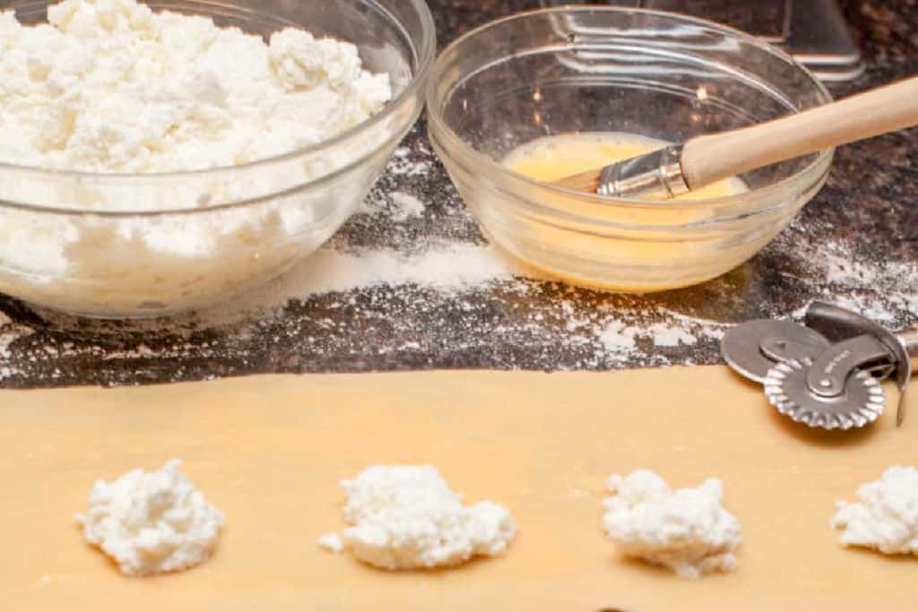 a sheet of fresh rolled pasta with some homemade ricotta lined up on it.