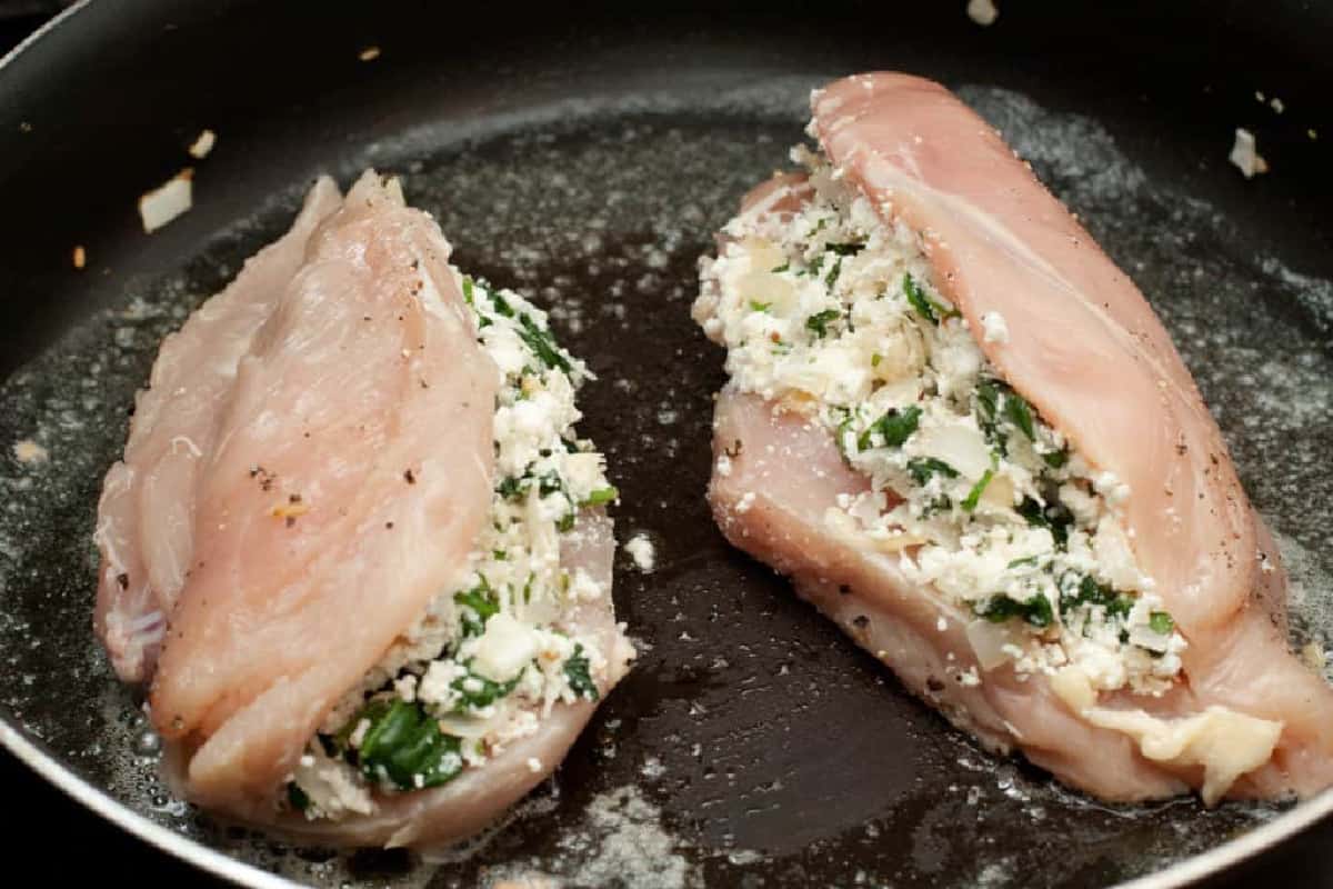raw stuffed chicken breasts in a saute pan.