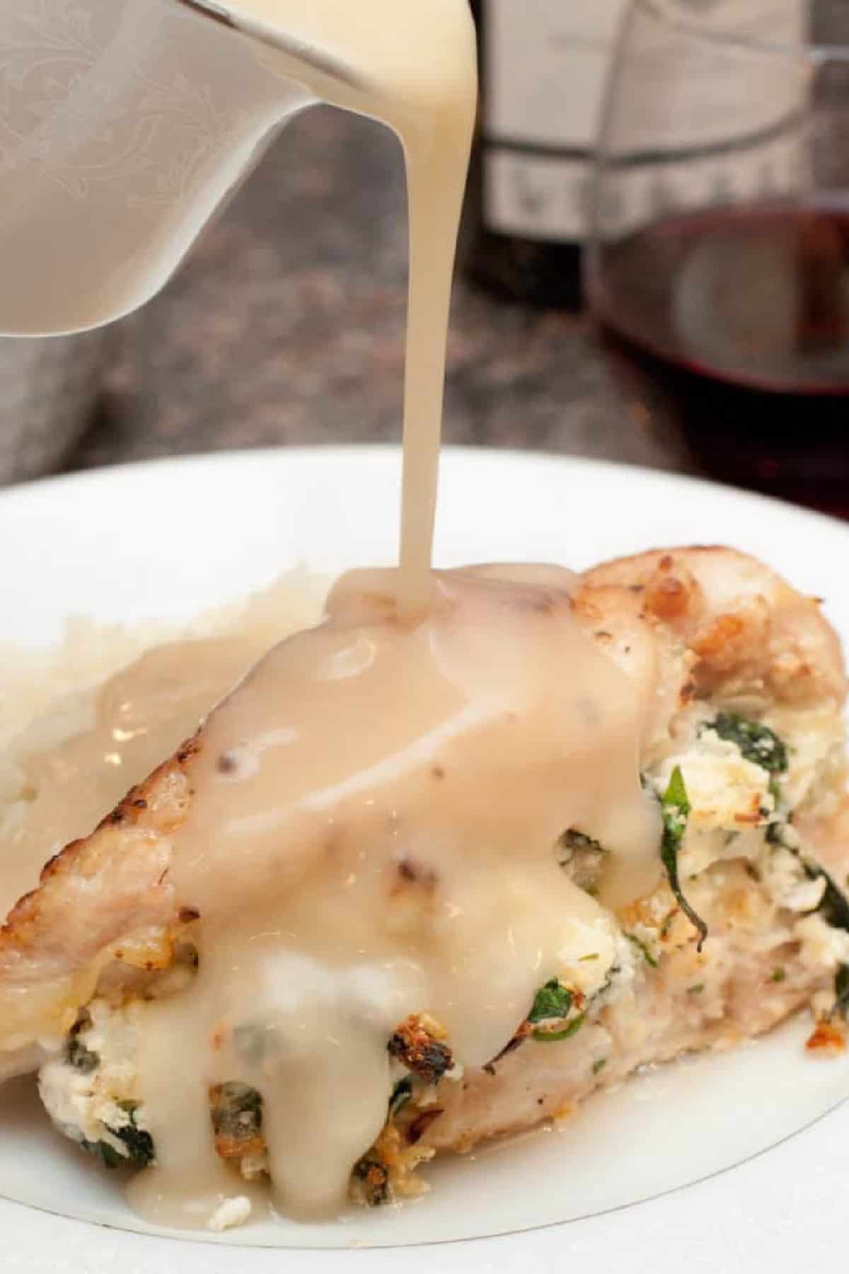 a stuffed chicken breast with gravy being poured on top.