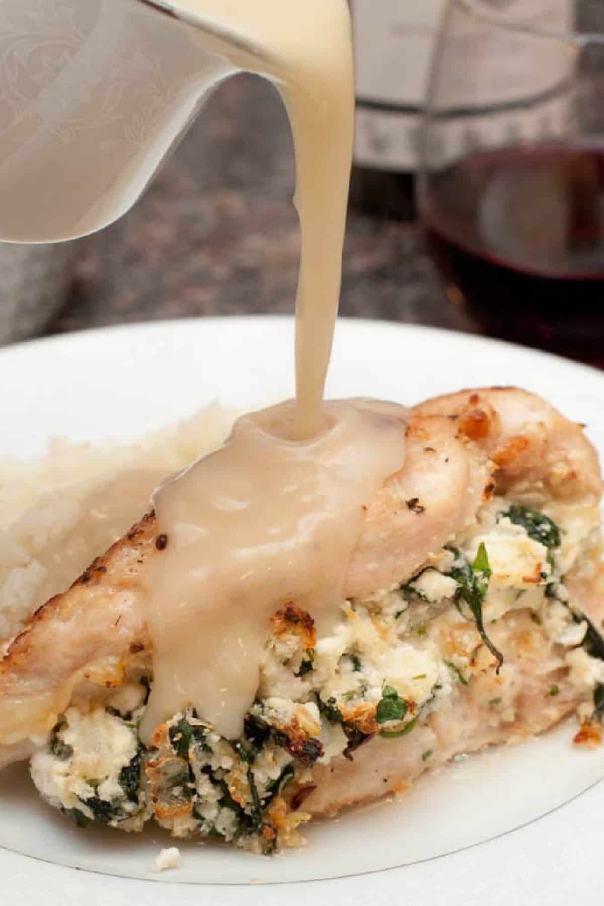 a stuffed chicken breast with gravy being poured on top.