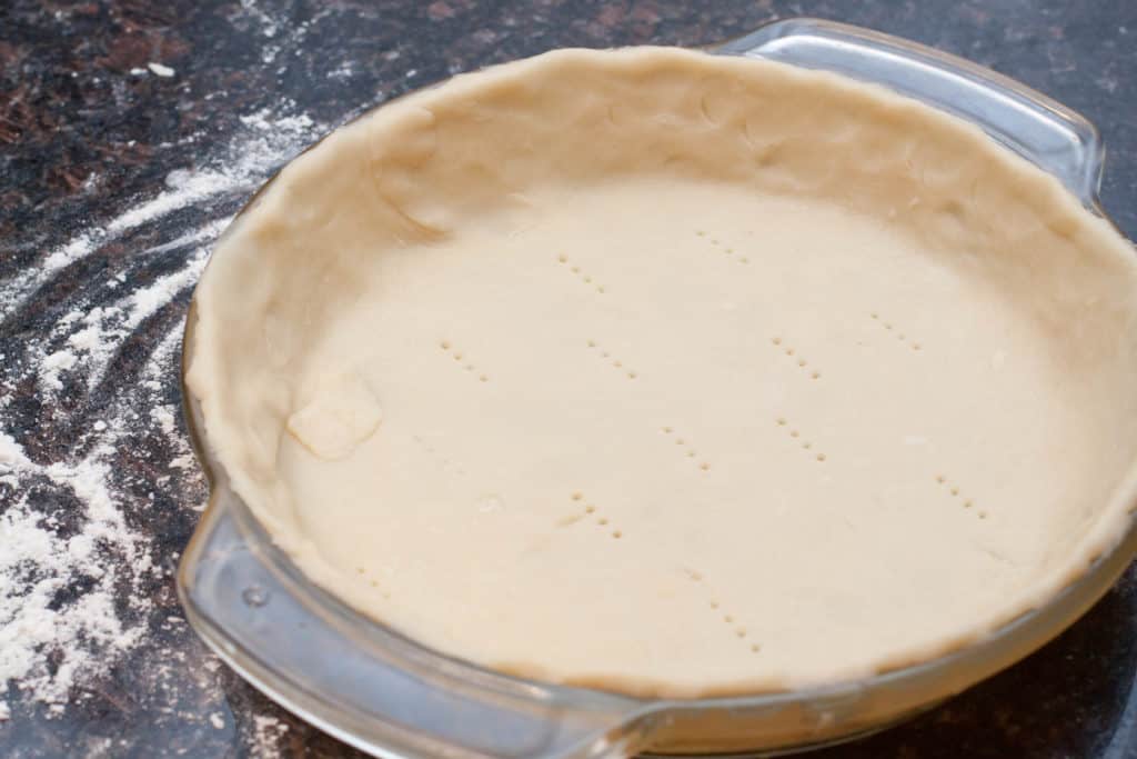 a pie dish with a raw dough fitted in.