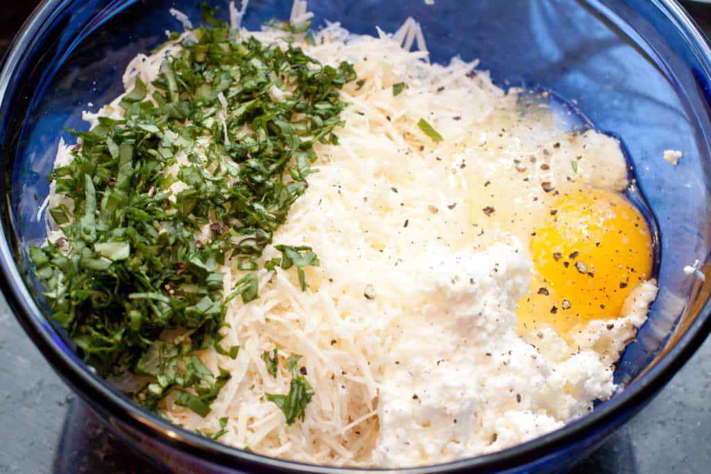 a bowl of fresh parsley, cheese, and an egg and pepper.