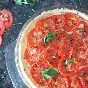 an overhead of a baked tomato pie with fresh basil.