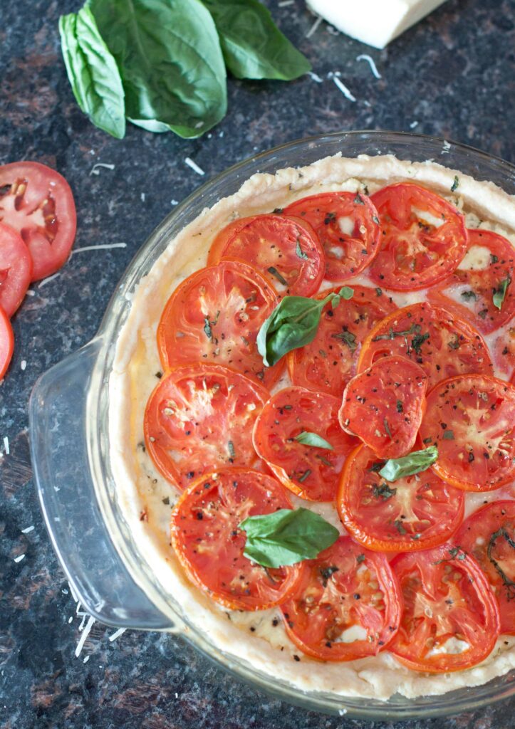 an overhead of a baked tomato pie with fresh basil.