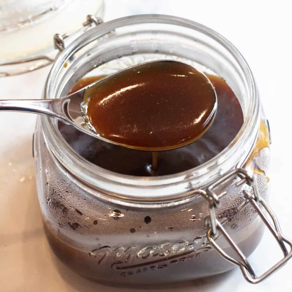 a spoon of teriyaki sauce over an open jar of sauce.