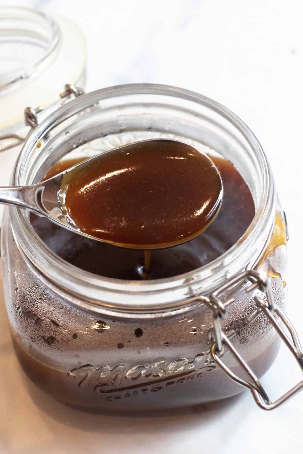 a spoon of teriyaki sauce over an open jar of sauce.