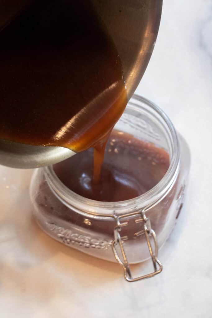 a pot pouring teriyaki sauce into an open mason jar.