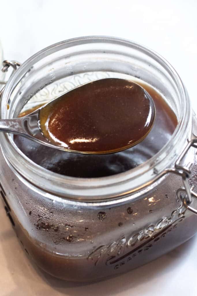 a spoon of teriyaki sauce over an open jar of sauce.