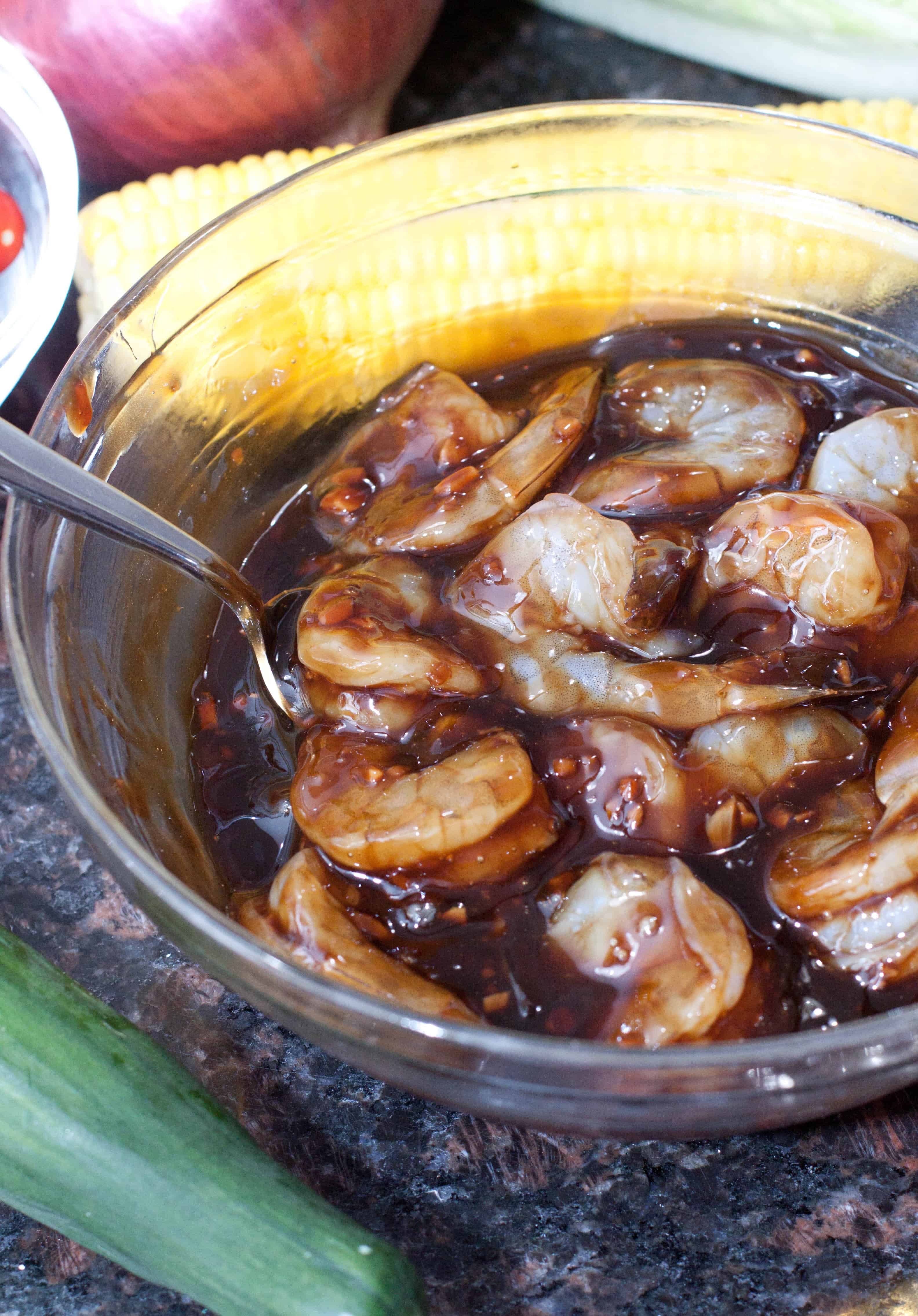 a bowl of raw shrimp marinating in sauce.