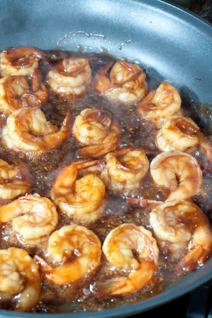 shrimp cooking in teriyaki sauce in a pan.
