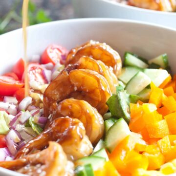 teriyaki shrimp salad in a bowl with dressing poured on top