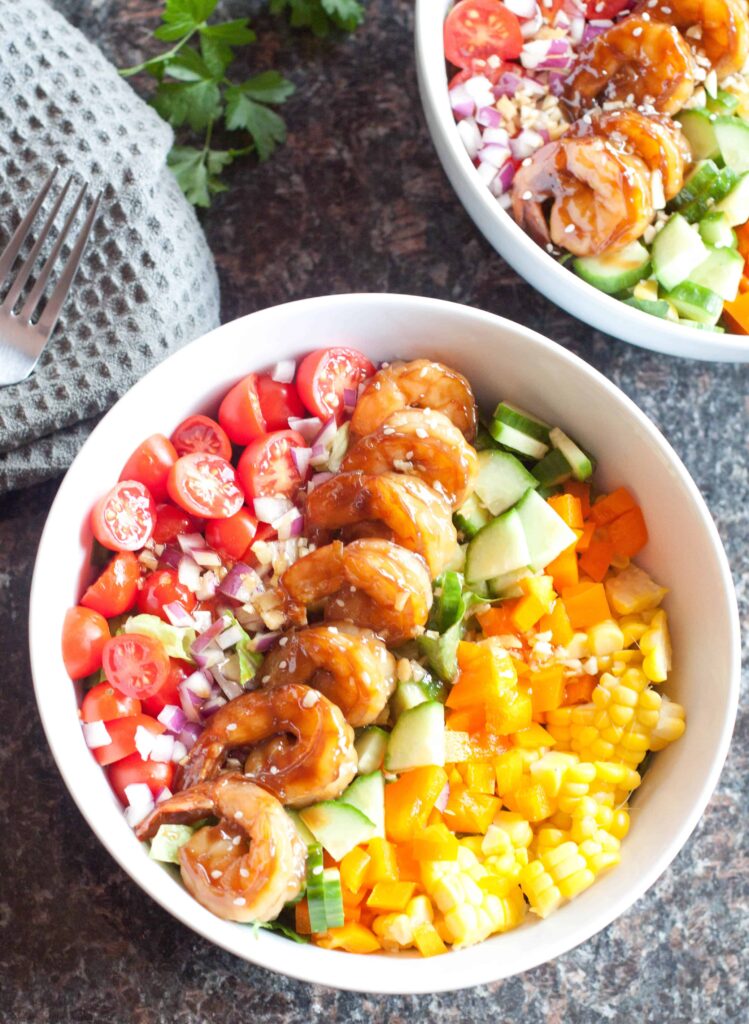 a bowl of teriyaki shrimp with chopped veggies.