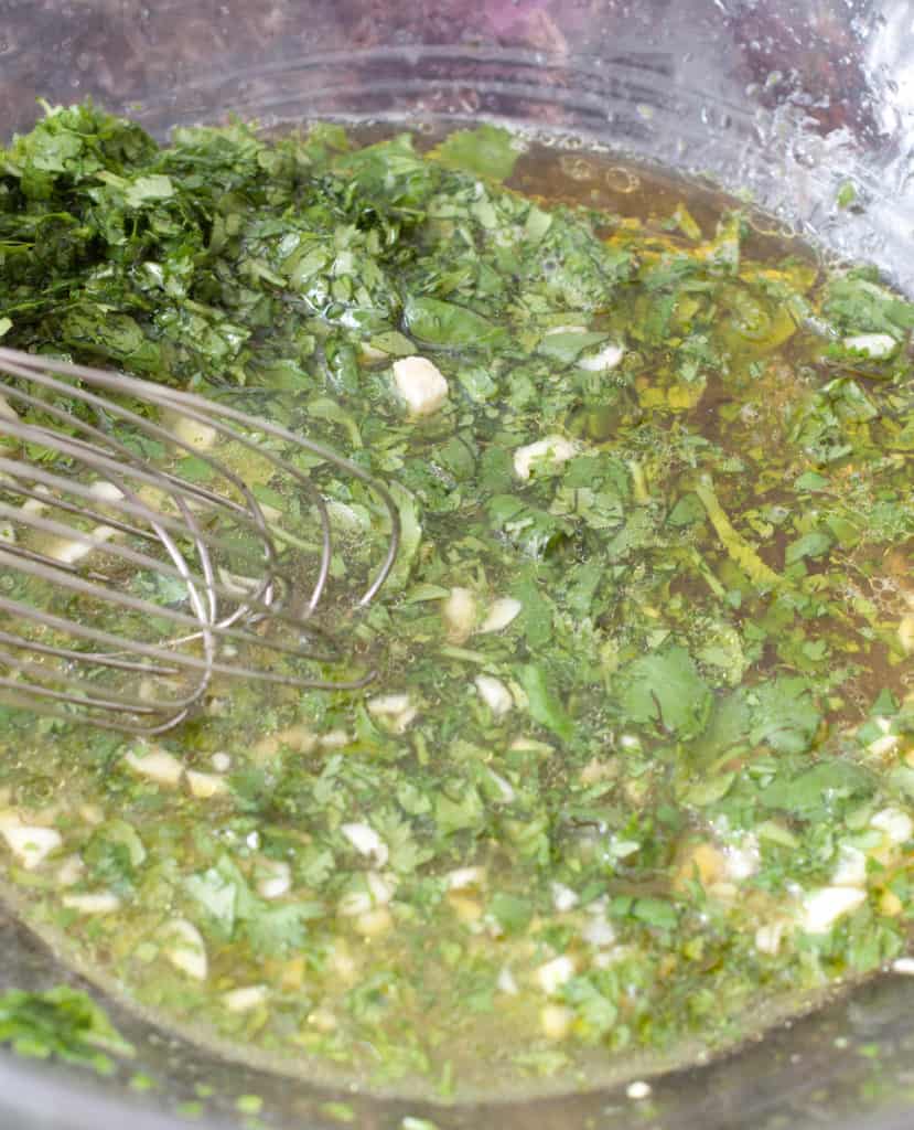 a bowl of cilantro, garlic, olive oil, honey, salt, lime juice all mixed together