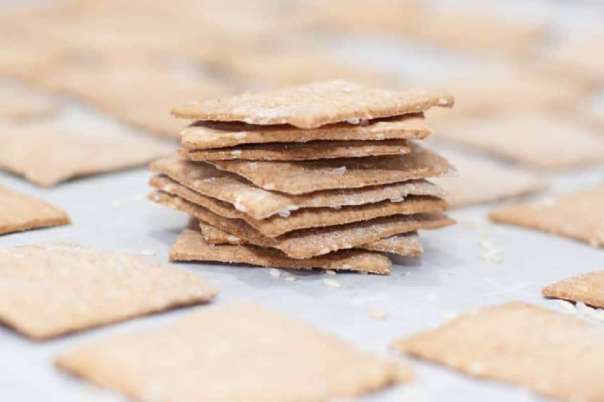 a stack of thin crackers on a baking sheet with other crackers.