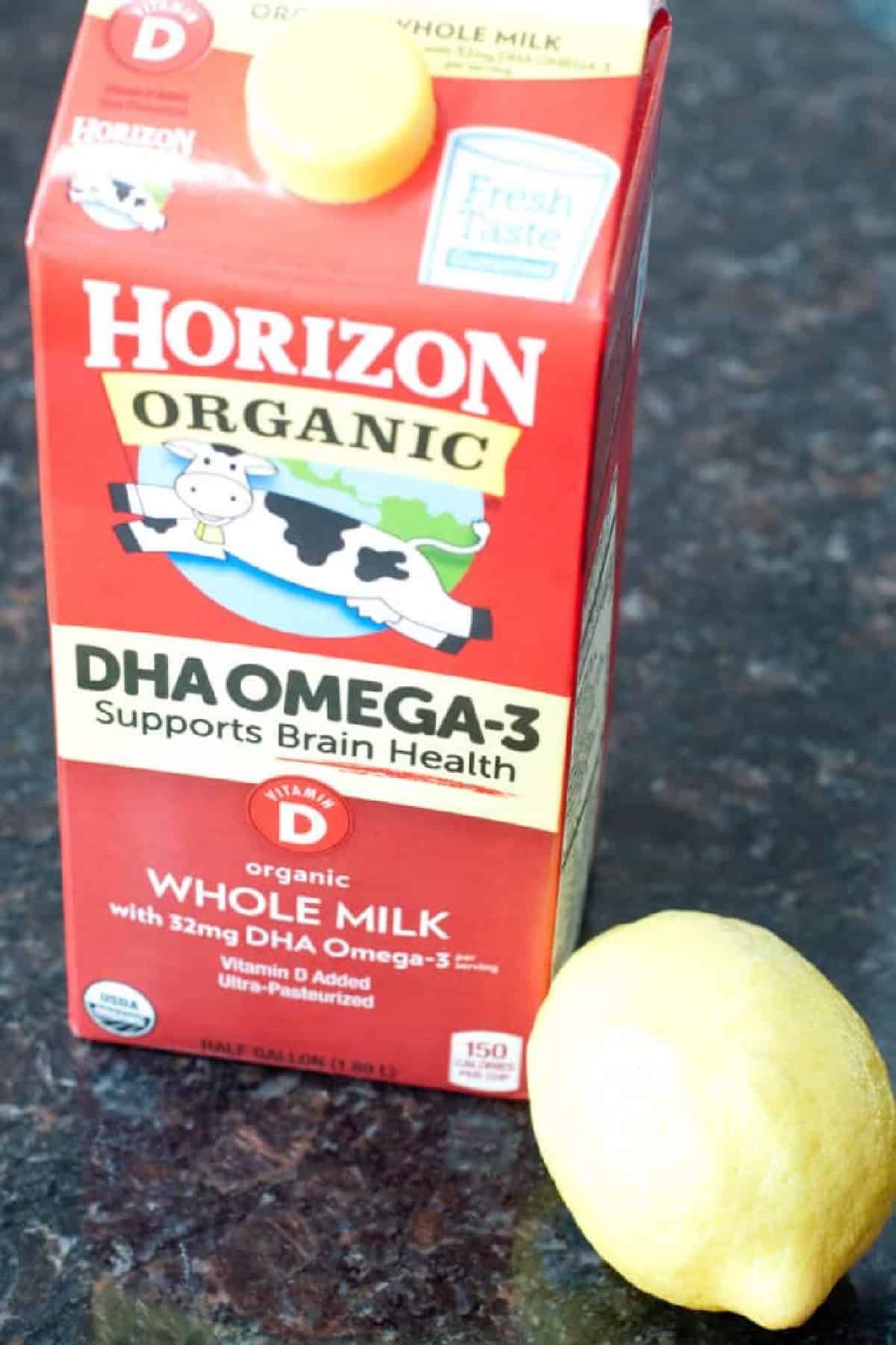 a carton of milk and a lemon on a counter.