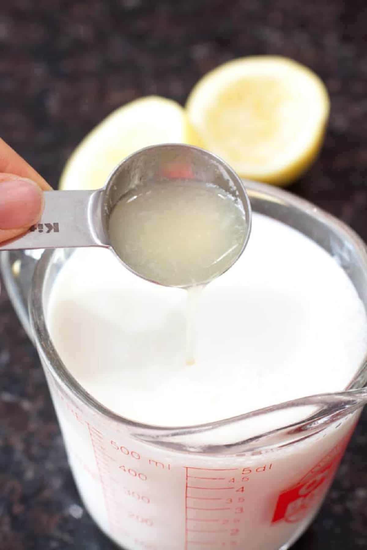 a tablespoon of lemon juice being poured into milk.
