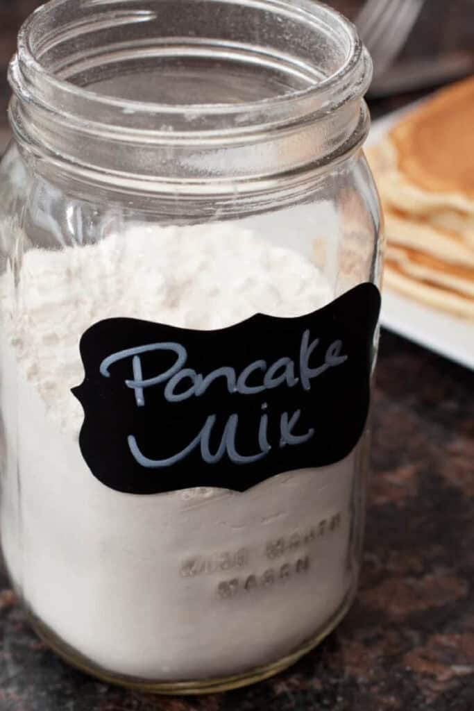 a jar of labeled pancake mix in front of some pancakes.
