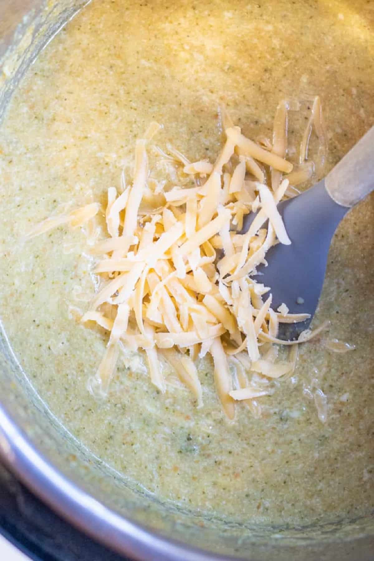 a pot with creamy soup and shredded cheese.