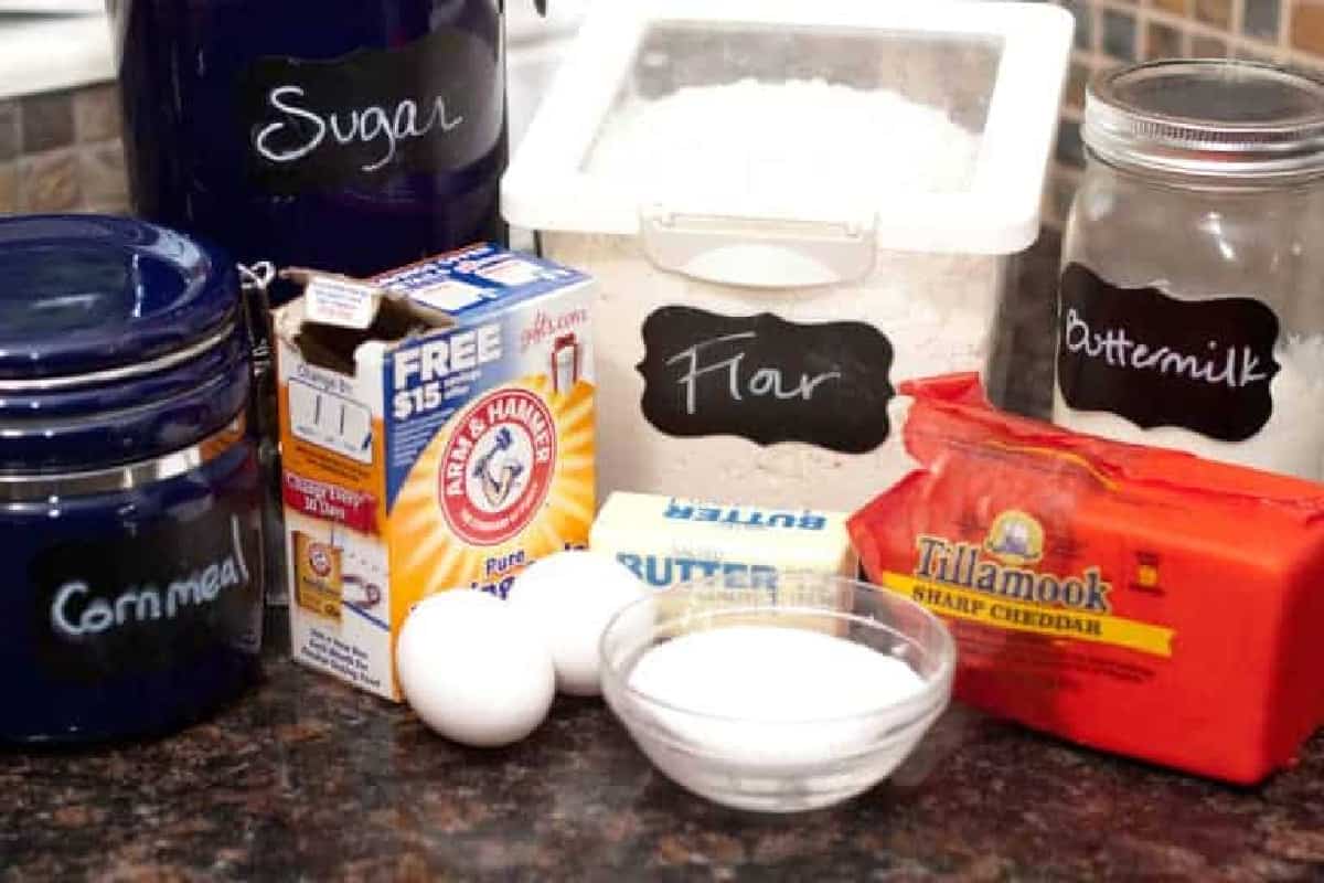 flour, sugar, cornmeal, cheese, eggs, baking soda on a counter.