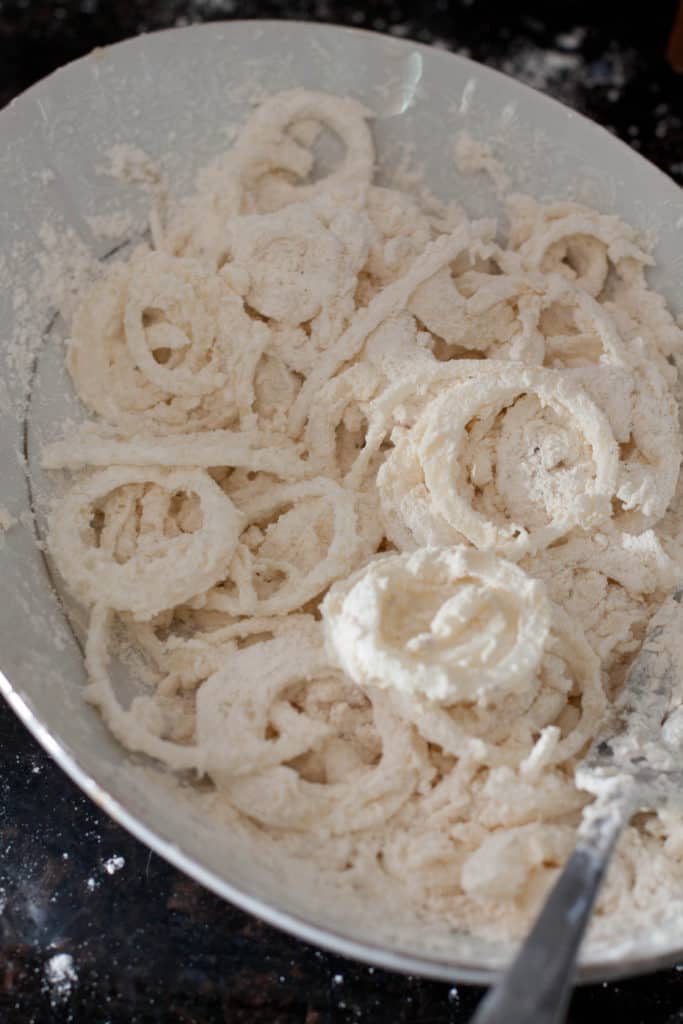 a bowl of flour coated onions.