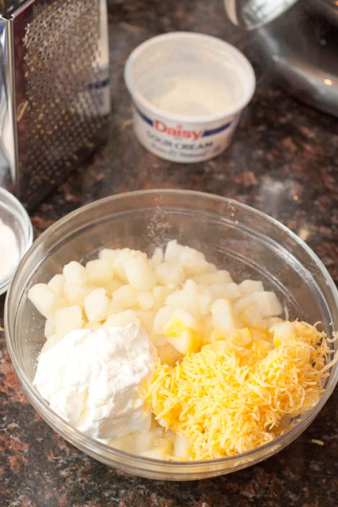 a bowl of boiled potatoes, sour cream, and cheese