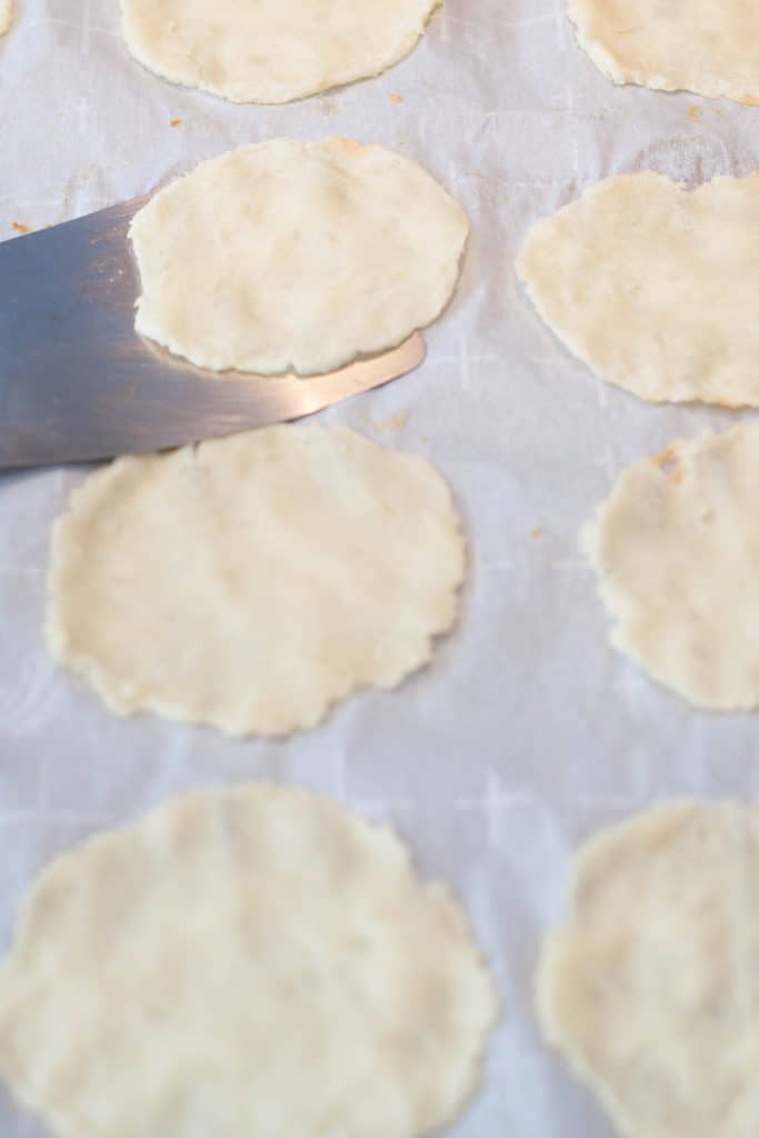 chip shaped mashed potatoes cooked on parchment paper and being scooped up with a spatula