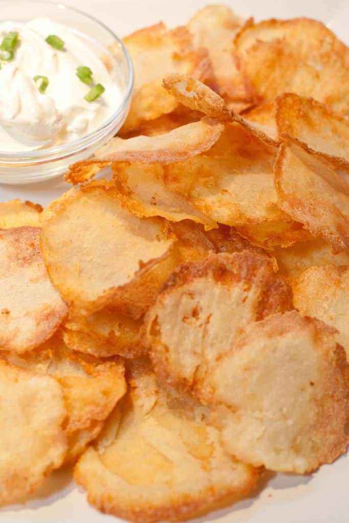 a plate of crispy chips with a bowl of dip