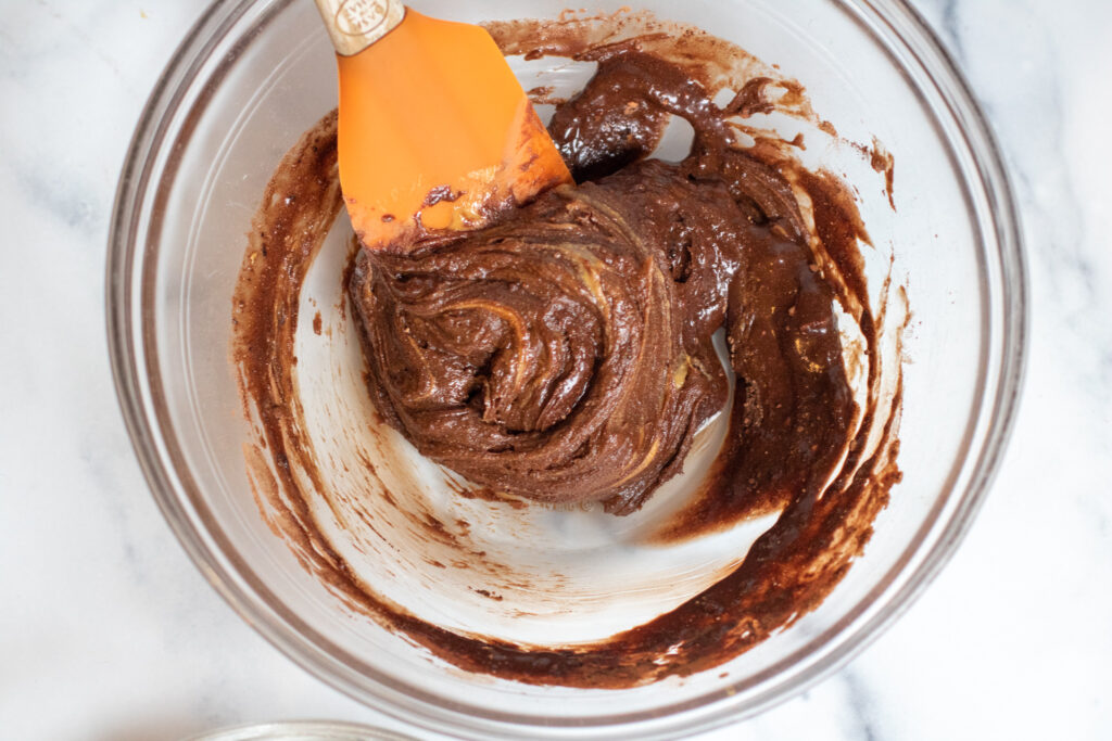 a bowl with a spatula mixing a chocolate mixture.