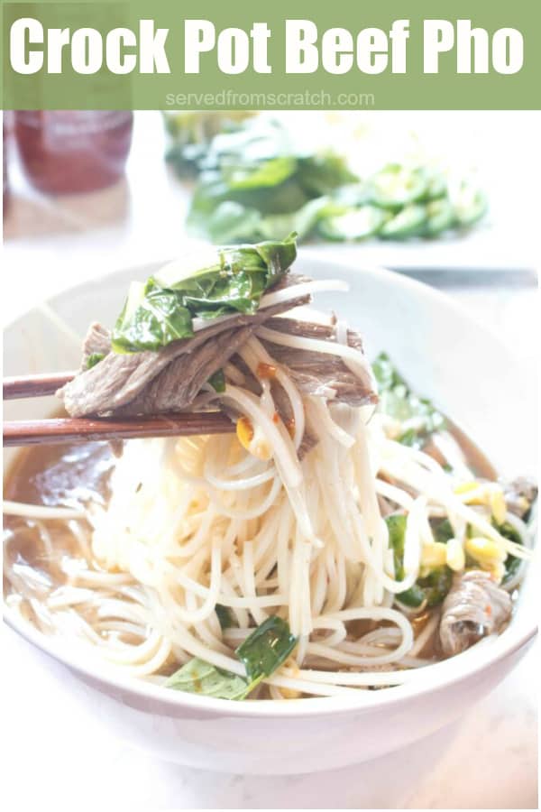 a bowl of beef pho with chopsticks holding a bite up with Pinterest Pin Text.