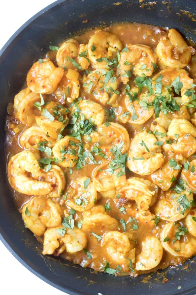 a pan of cooked shrimp in curry. 