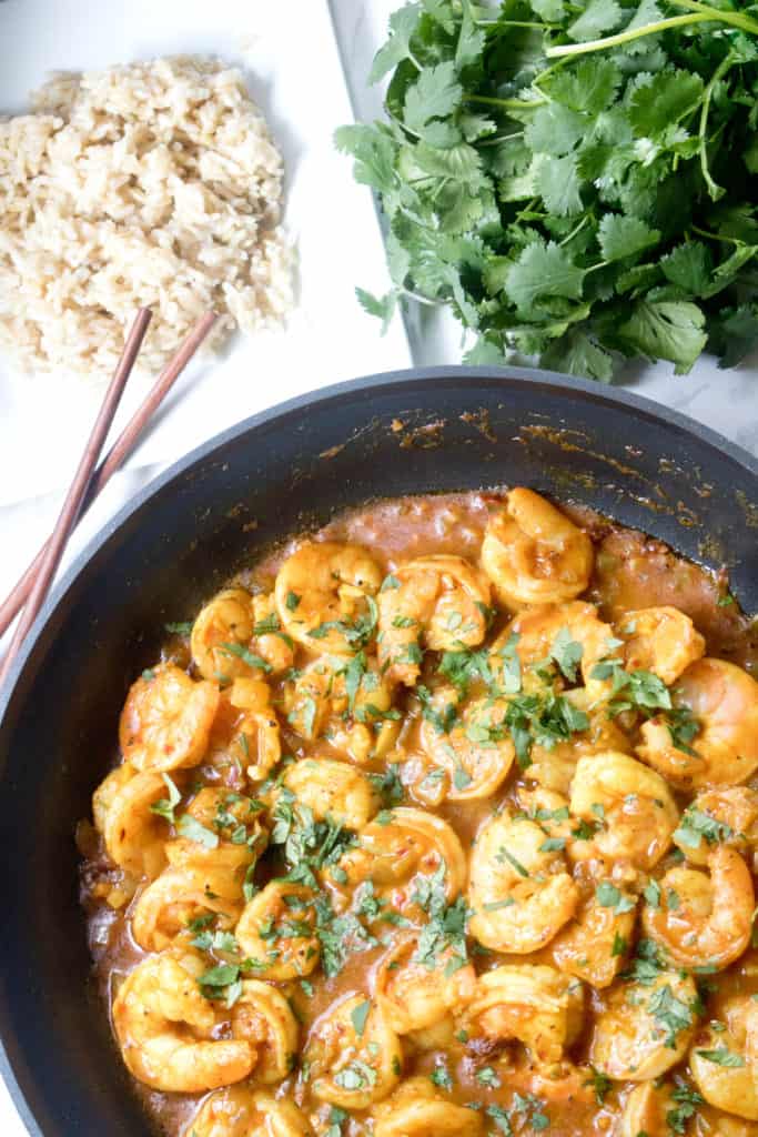 a pan of shrimp curry with cilantro and brown rice.