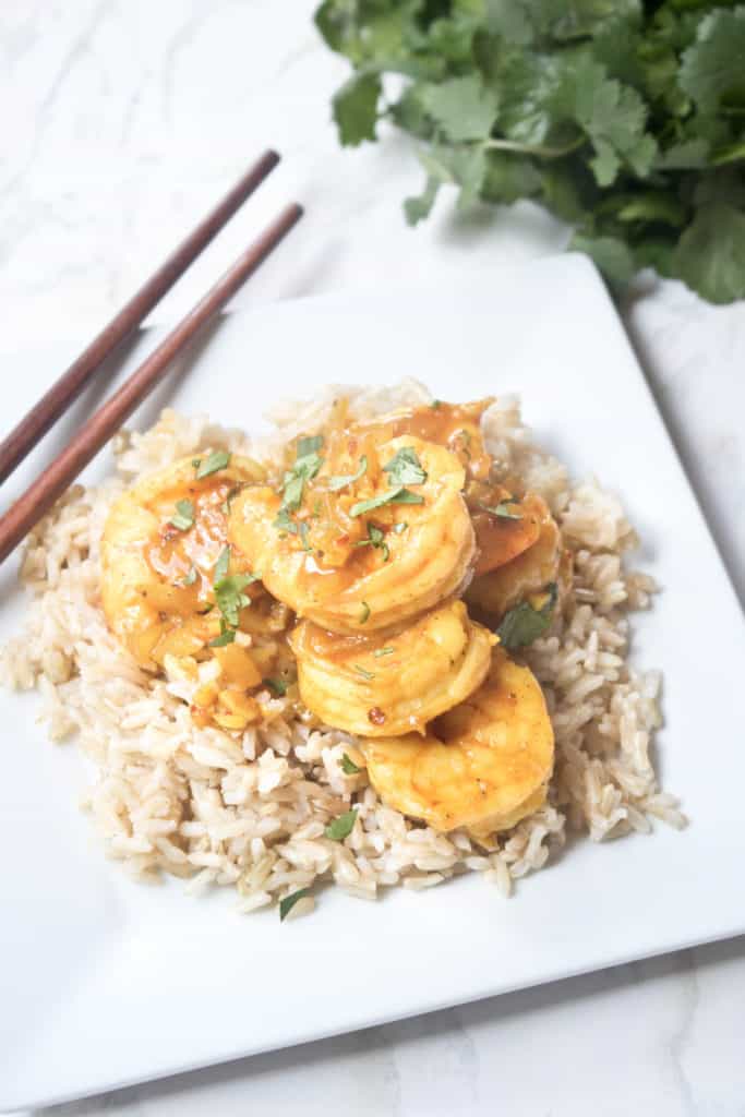 a plate of rice and shrimp curry with chopsticks.