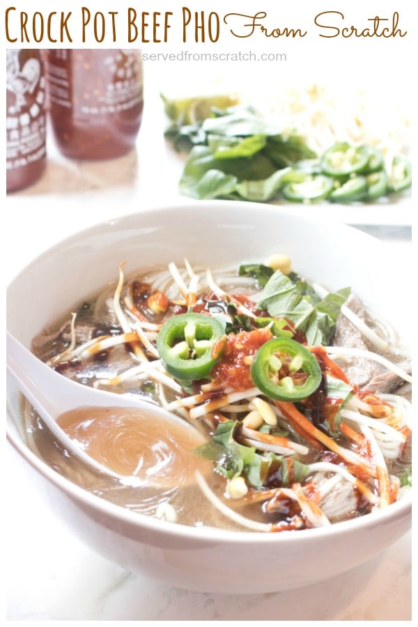 a bowl of pho with a spoon and topped with sliced jalapenos