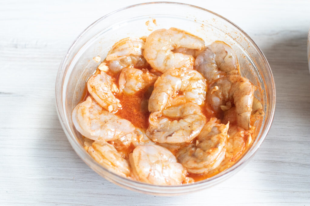 a bowl of raw shrimp with a marinade.