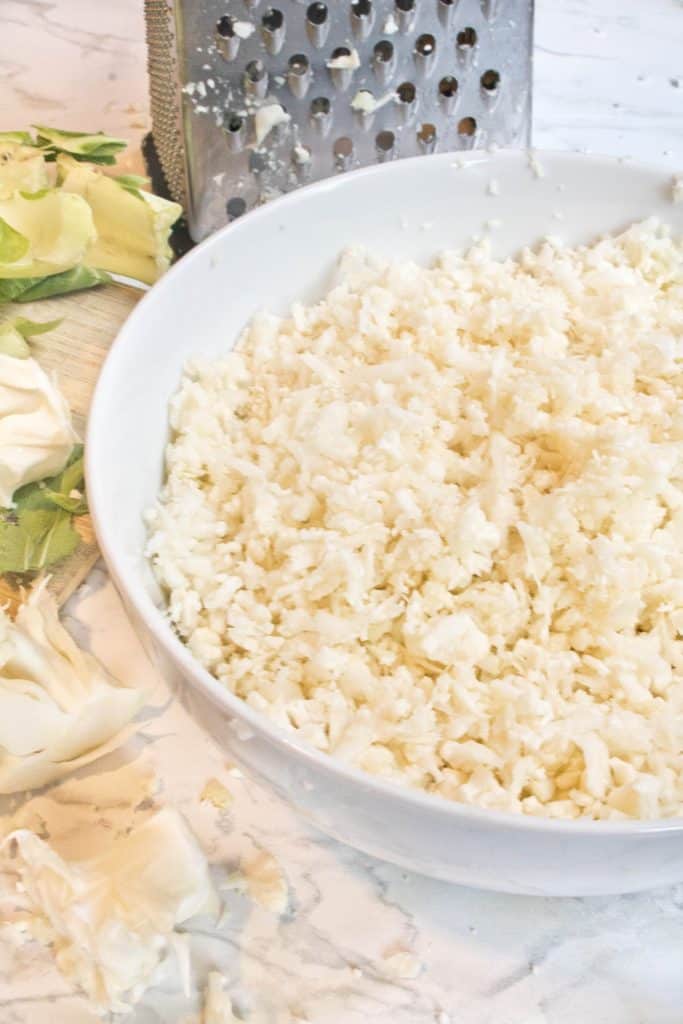 box grater and riced cauliflower in a bowl