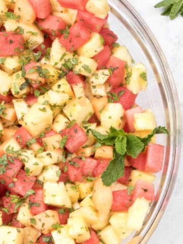 a bowl of pineapple melon and watermelon with mint.