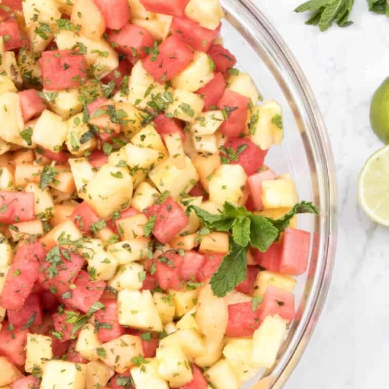 a bowl of pineapple melon and watermelon with mint.