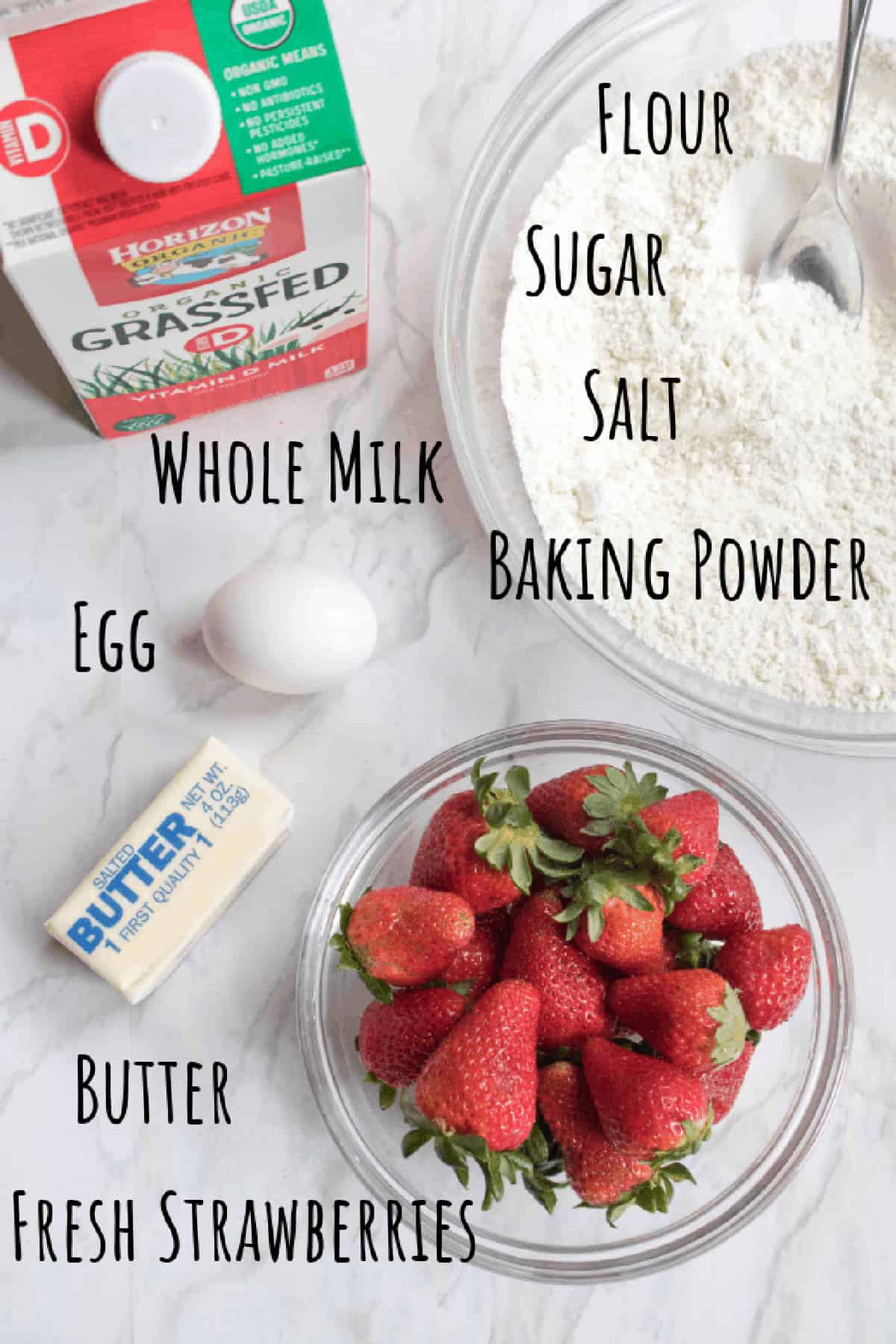 strawberries, milk, bowl with flour, butter, egg on counter.