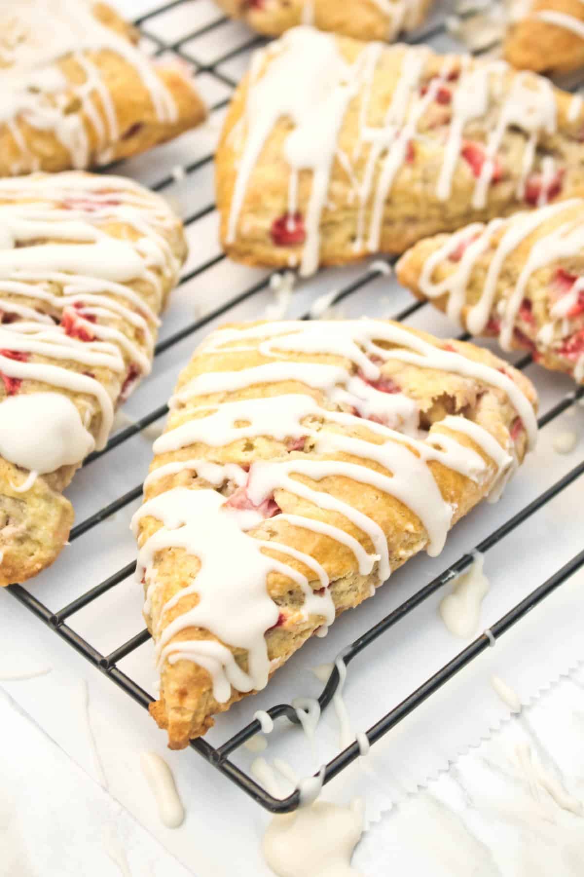 glazed scones with strawberries on a cooling rack.