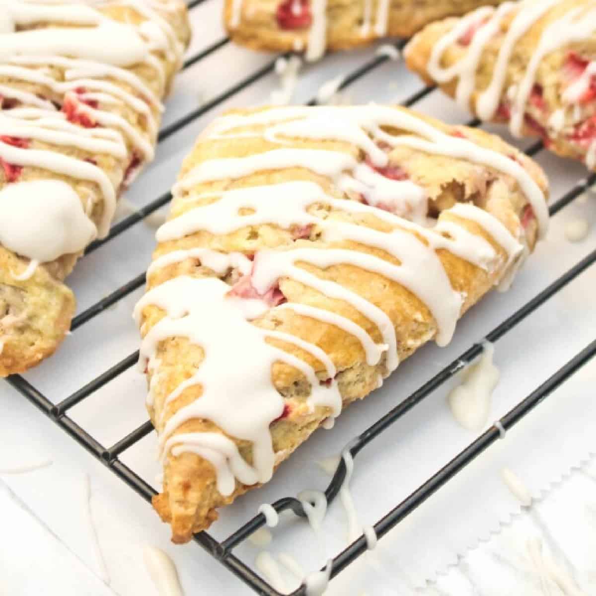 glazed scones with strawberries on a cooling rack.