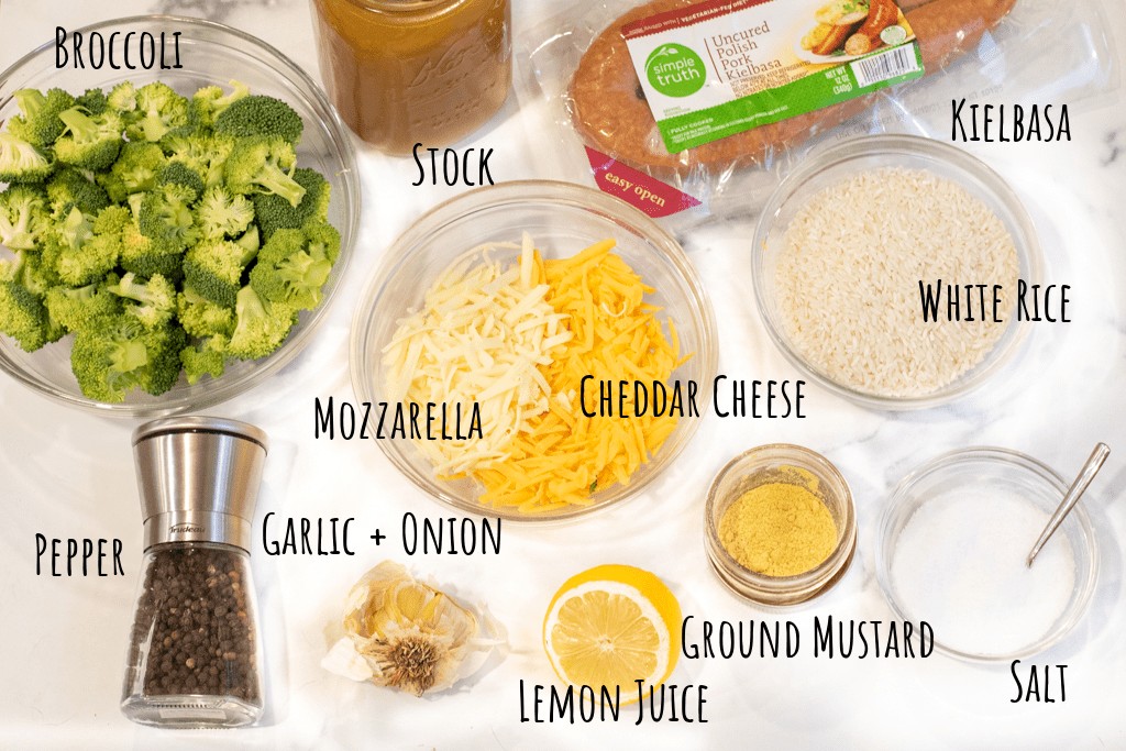 broccoli, cheeses, kielbasa, rice, spices, lemon and garlic on counter.