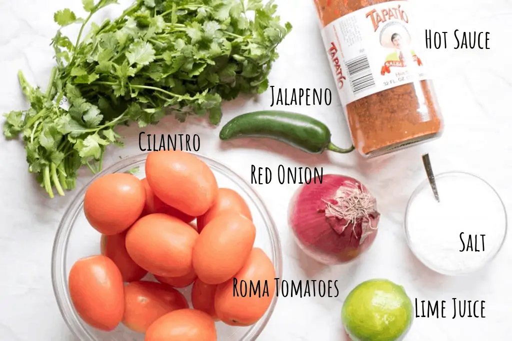 tomatoes, cilantro, jalapeno, hot sauce, lime, onion and salt on counter.