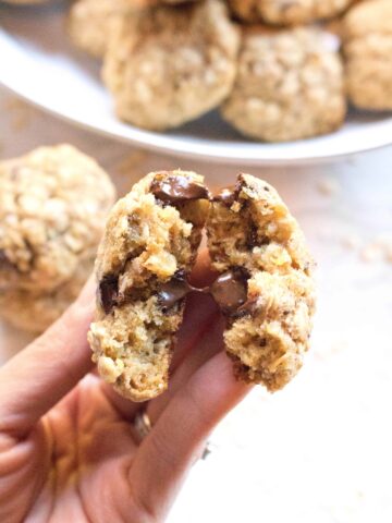 a hand holding a cookie with melted chocolate chips in half