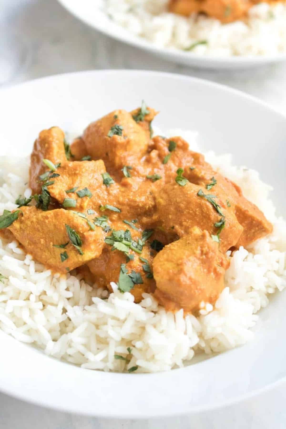 a plate of a bed of rice with chicken tikka masala on top.